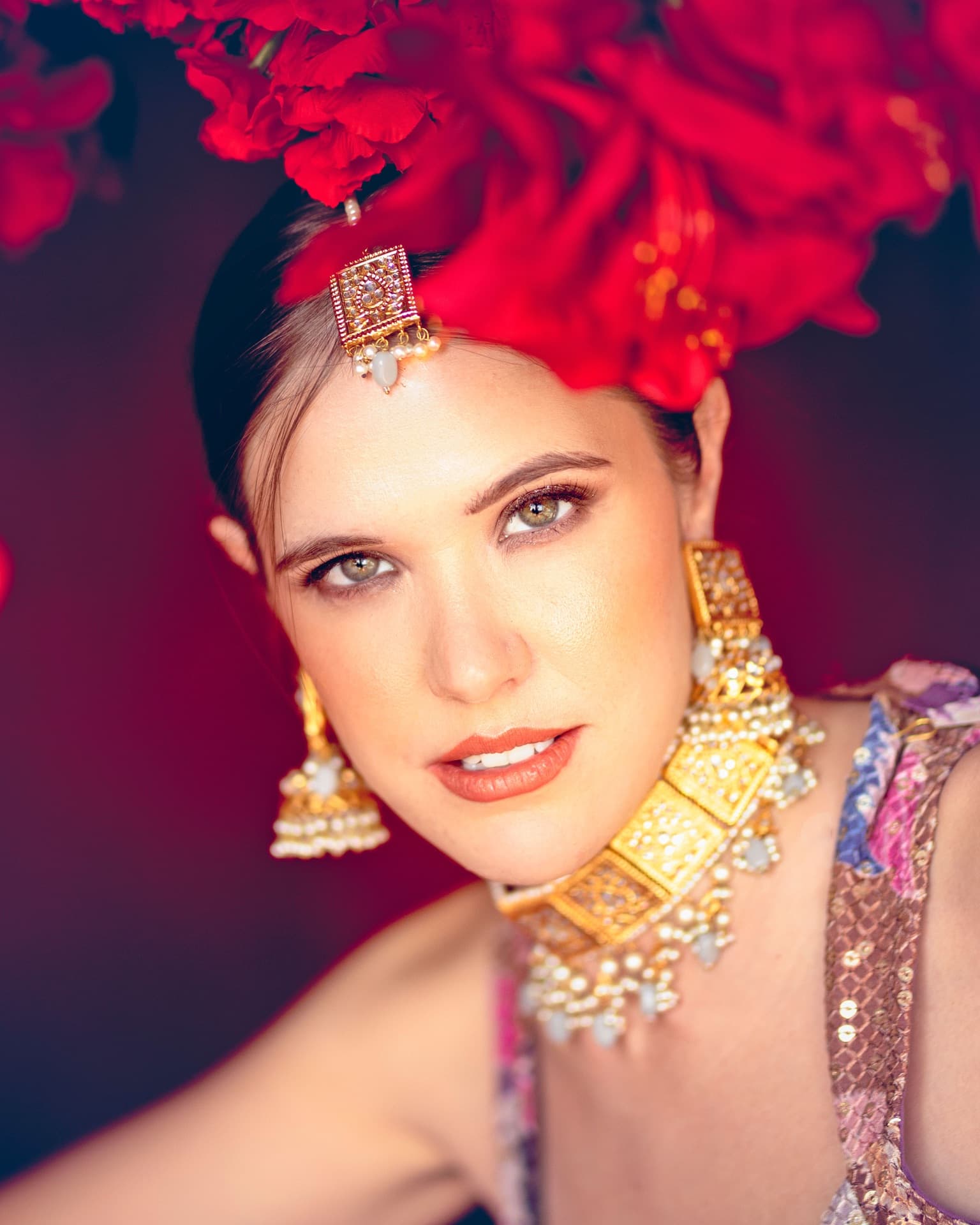 Bold bridal styling with red floral headpiece and gold jhumka earrings