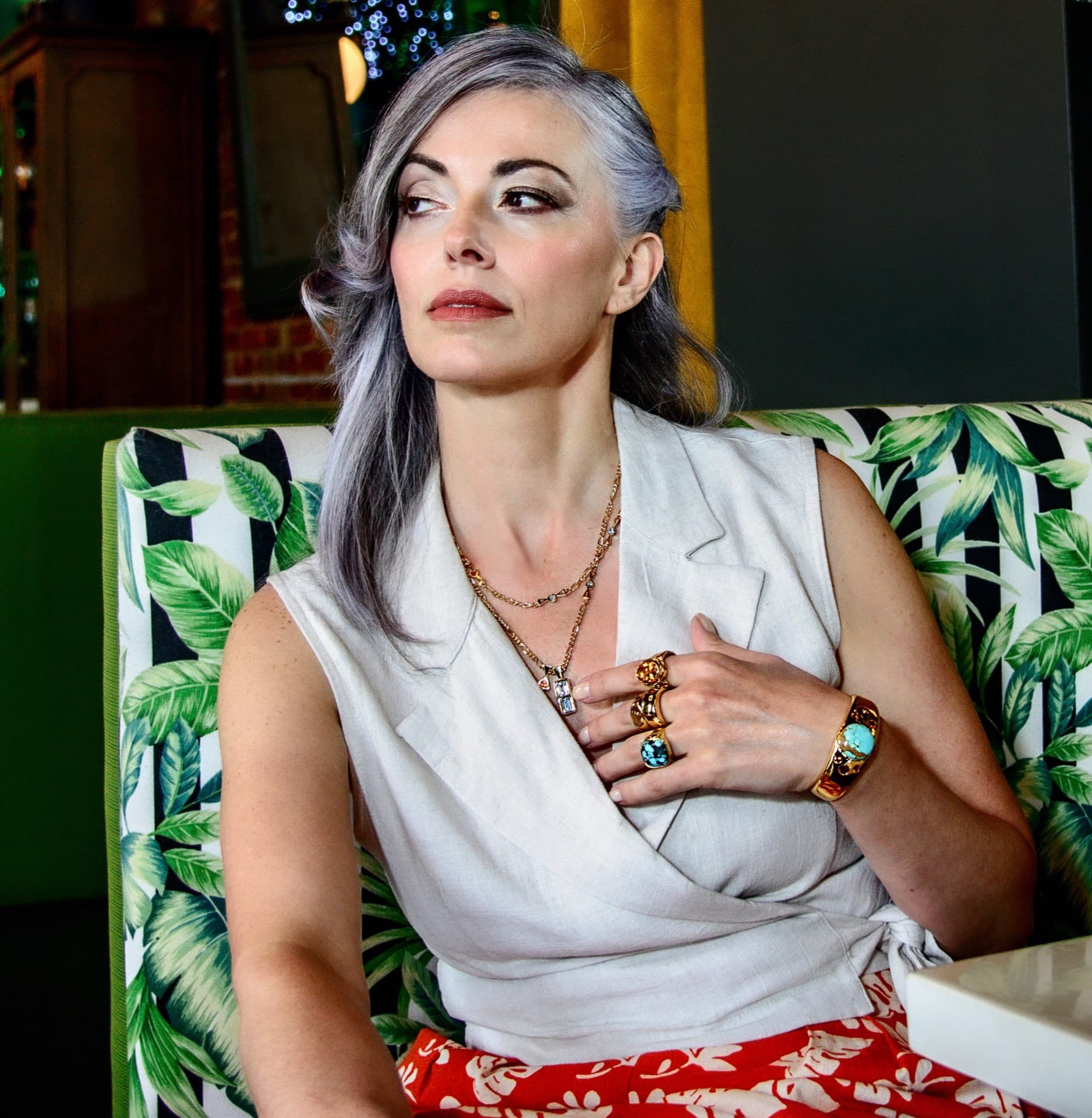 Silver-haired model with layered gold necklaces and turquoise statement rings